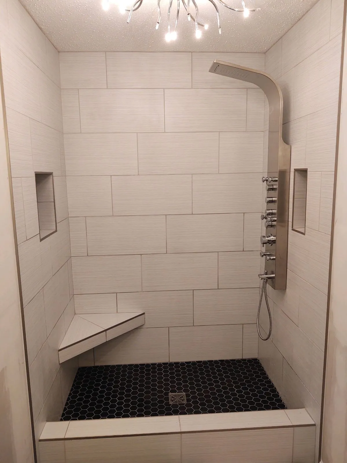 Custom bench seating and double shower niches in tiled shower remodel