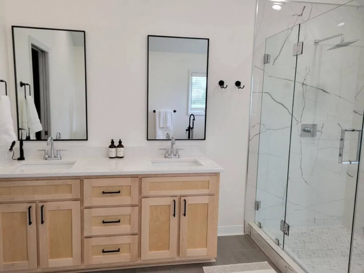 Modern bathroom renovation with frameless shower and wood vanity