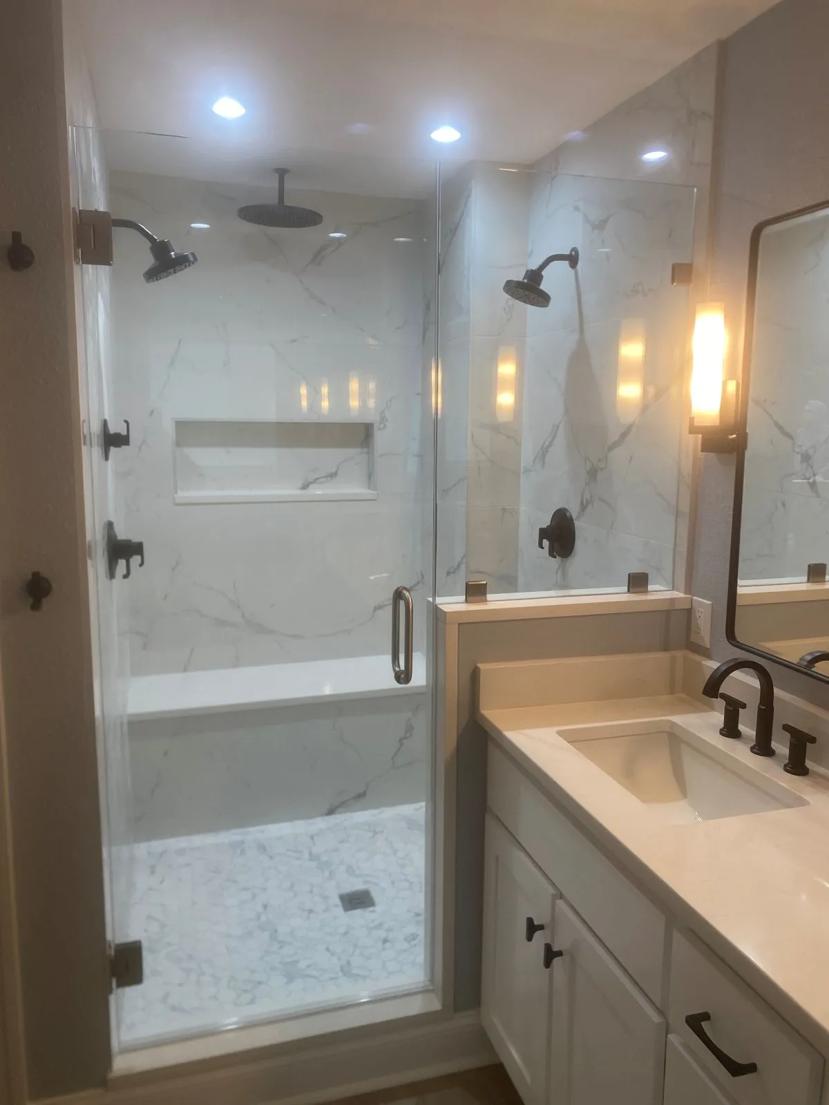 Frameless shower remodel with bench seating and brushed nickel fixtures