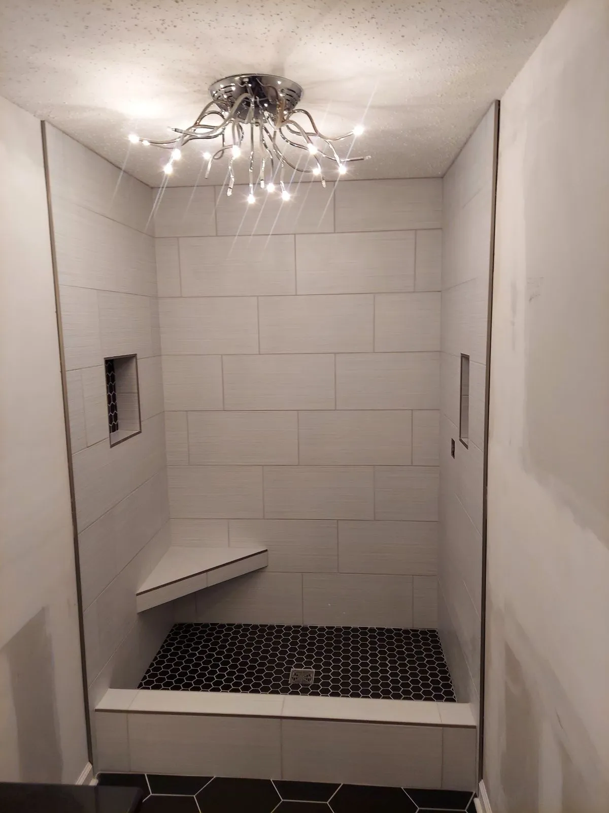 White subway tile shower with niche and modern light fixture
