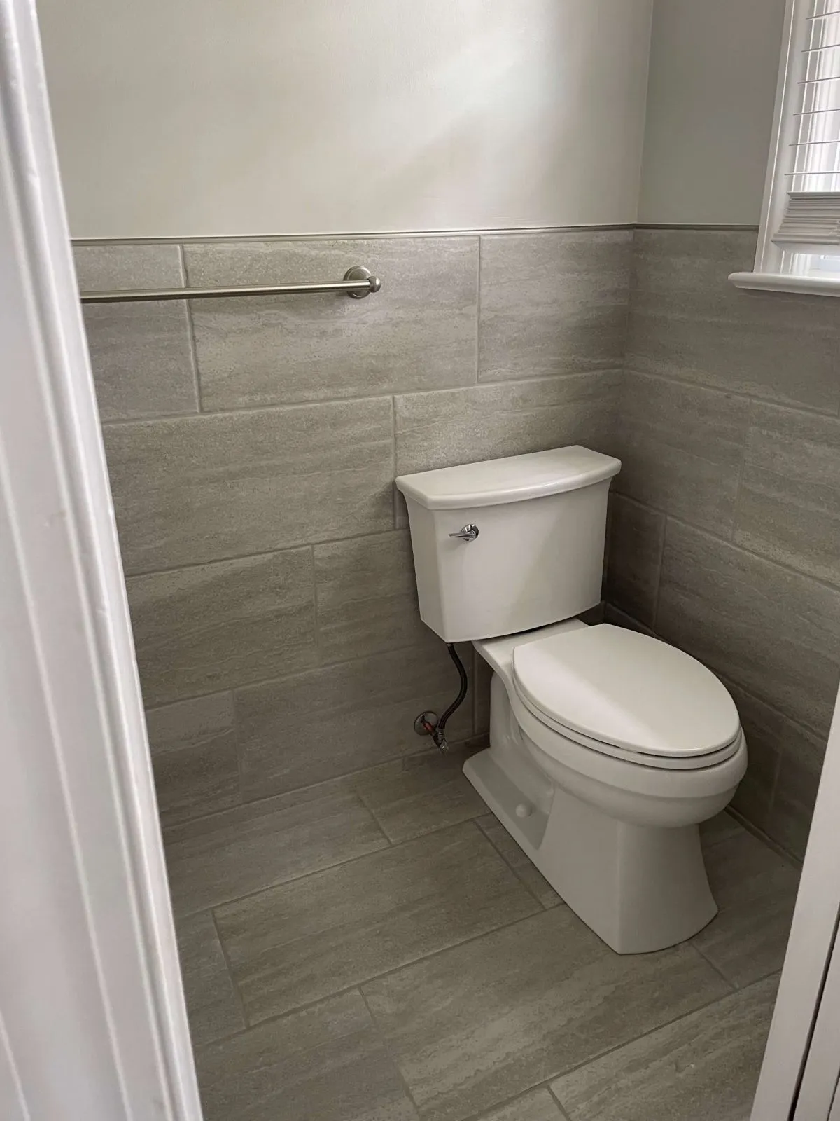 Compact gray tile walls and updated toilet.
