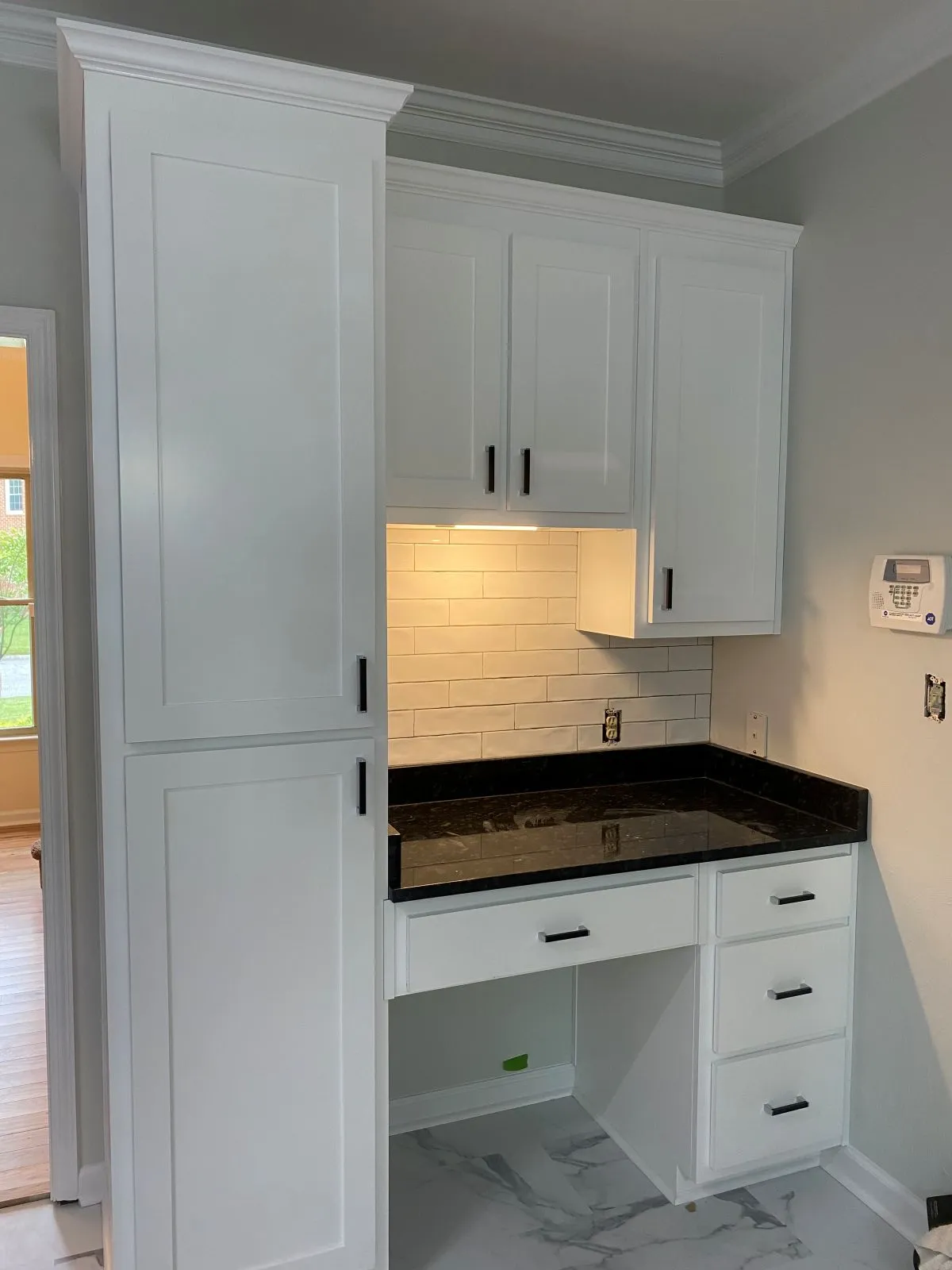 White glass-front cabinets with undercabinet lighting and wine rack in kitchen remodel