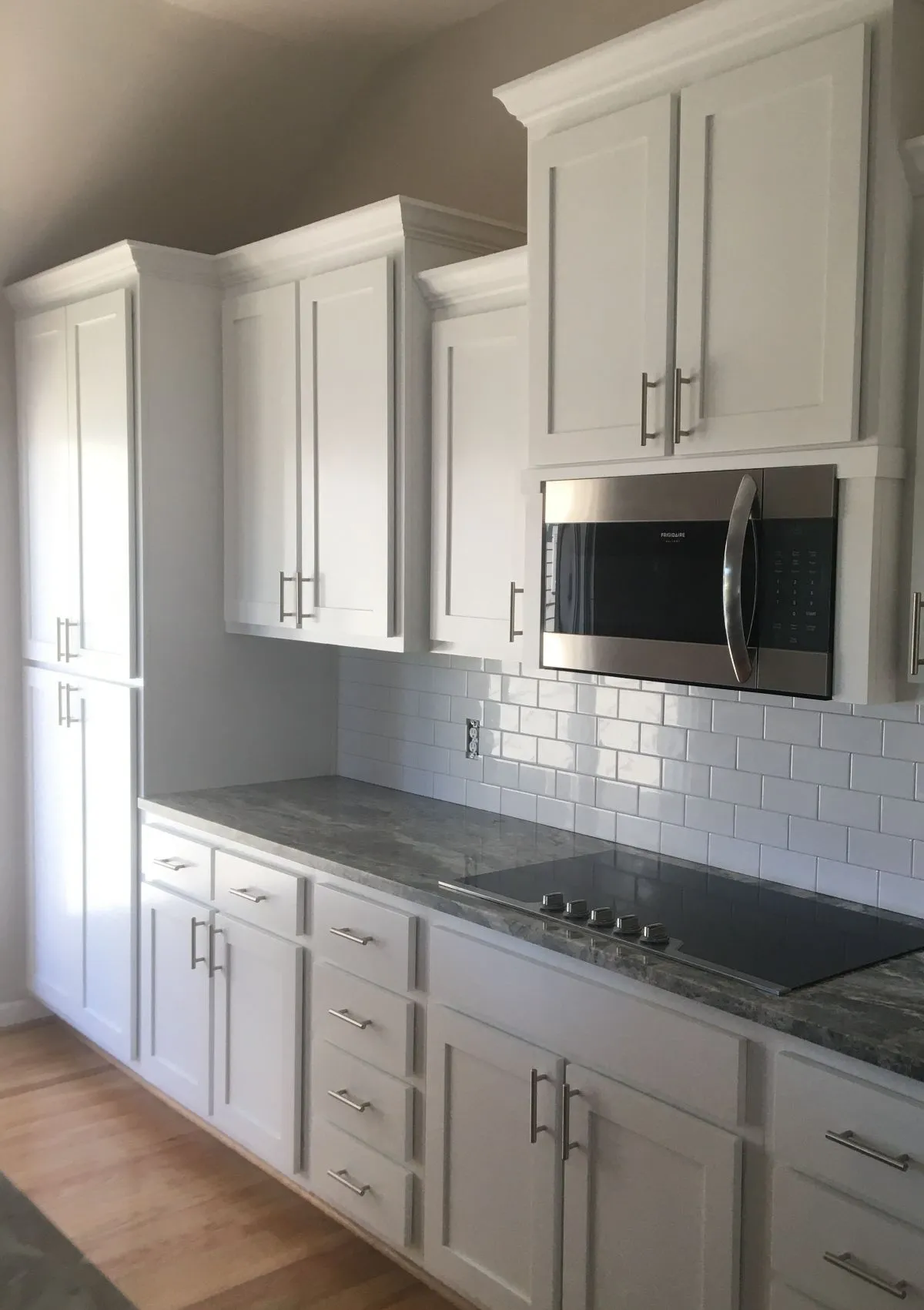 White cabinets with tile backsplash and microwave built-in