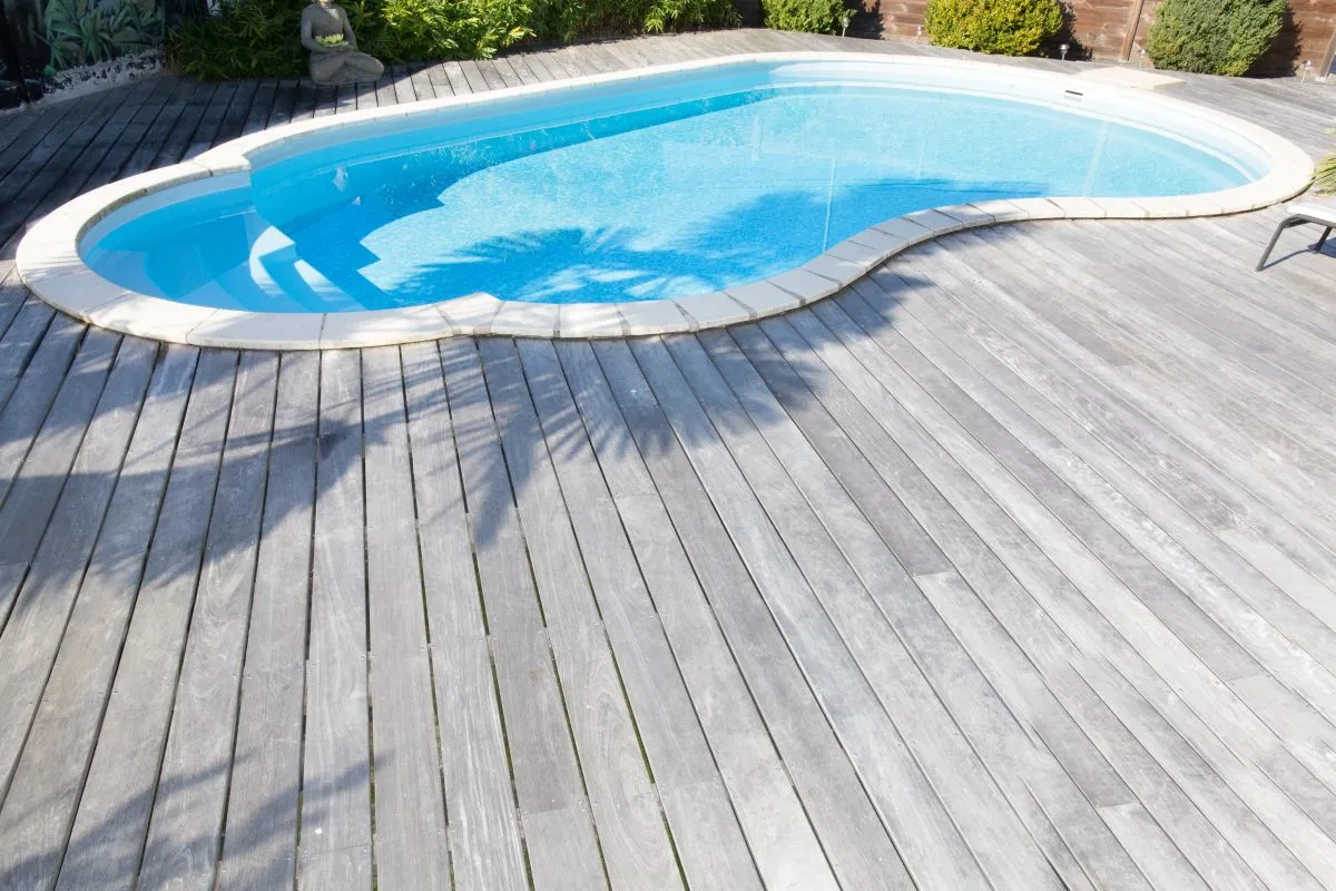 Custom deck installation around inground pool with pressure-treated wood planks