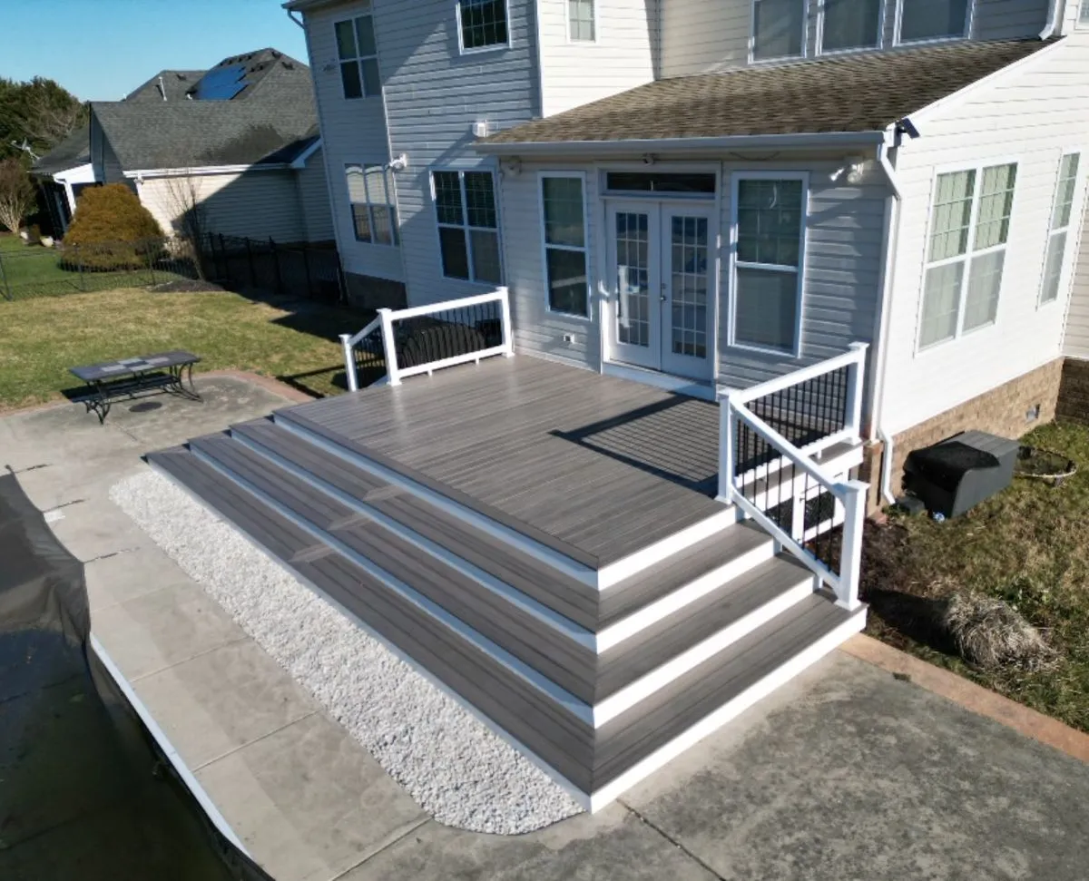 Low-profile composite deck with clean white railings and wide gray steps in a Chesapeake backyard