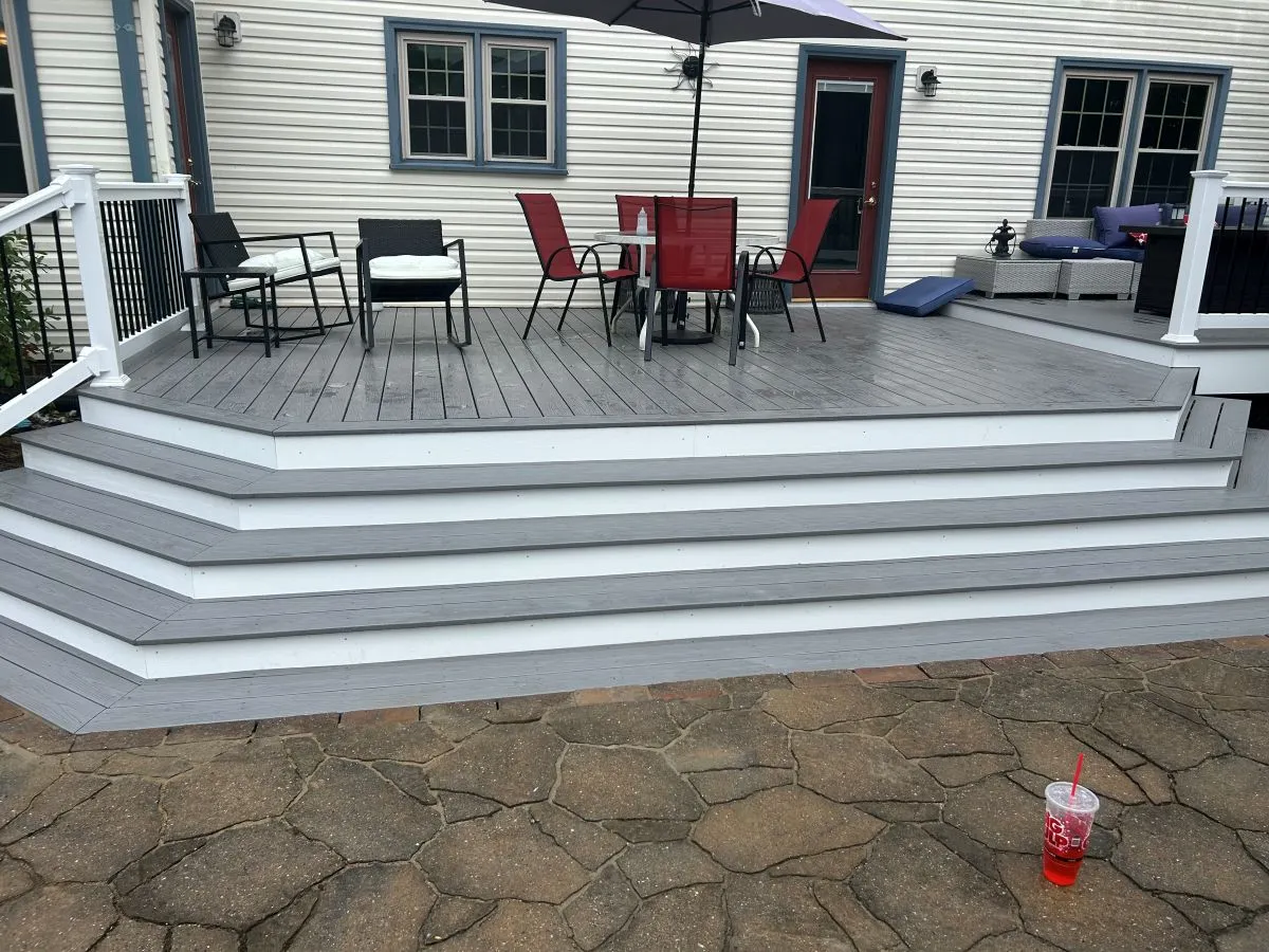 Spacious gray deck with wraparound stairs and outdoor dining setup in Virginia Beach
