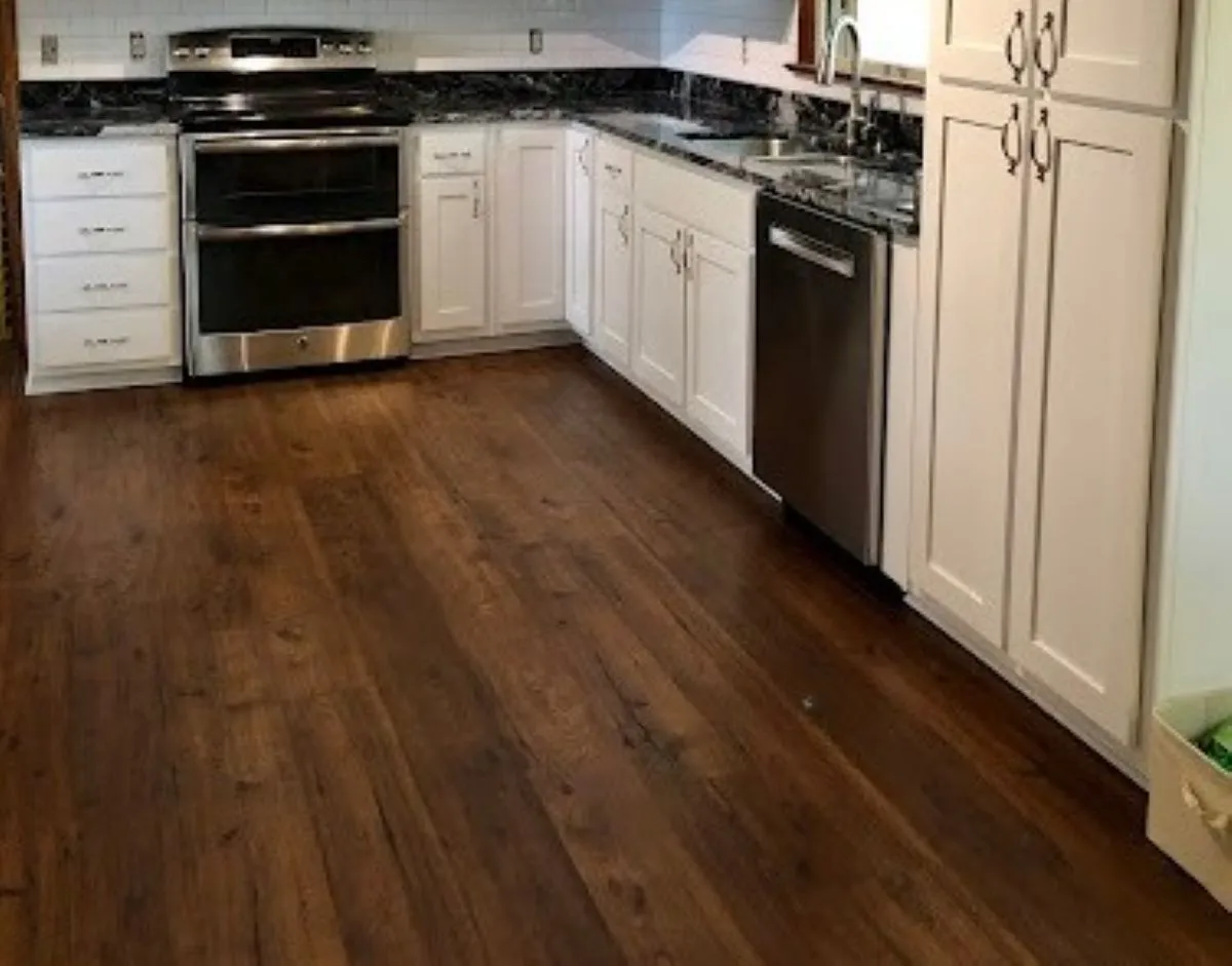 Luxury vinyl plank flooring installed in remodeled kitchen with white cabinetry