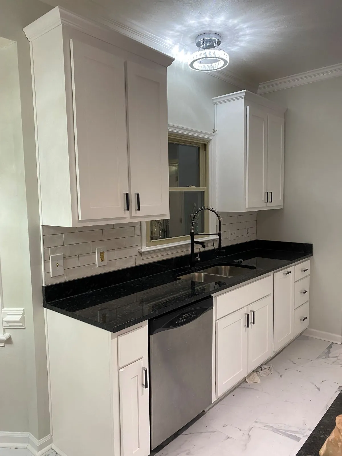 Kitchen remodel with white cabinets, black counters, and apron sink