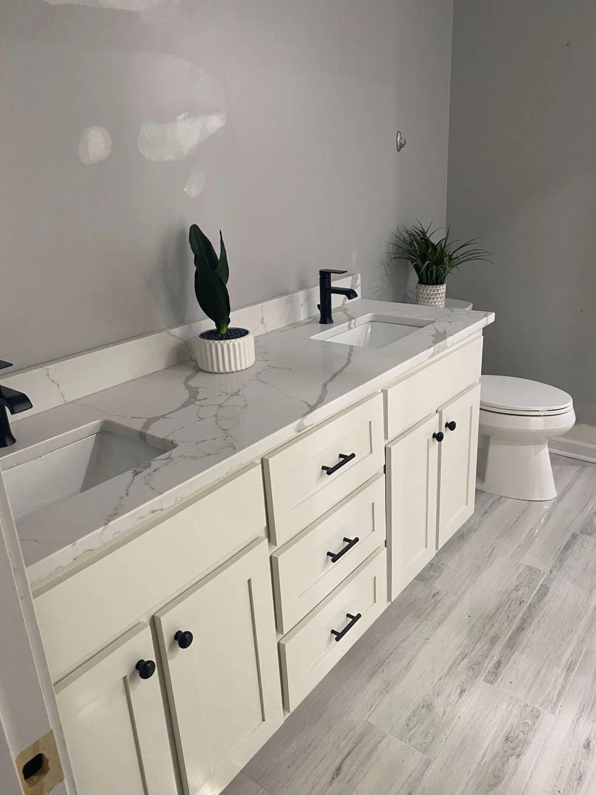 Double vanity installation with white cabinets and gray flooring