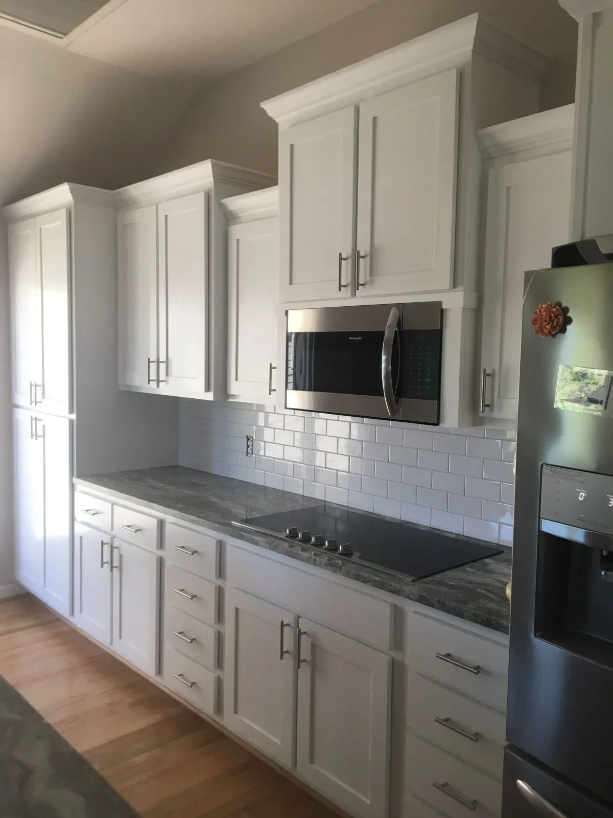 Modern kitchen with subway tile backsplash, flat cooktop, and brushed nickel hardware