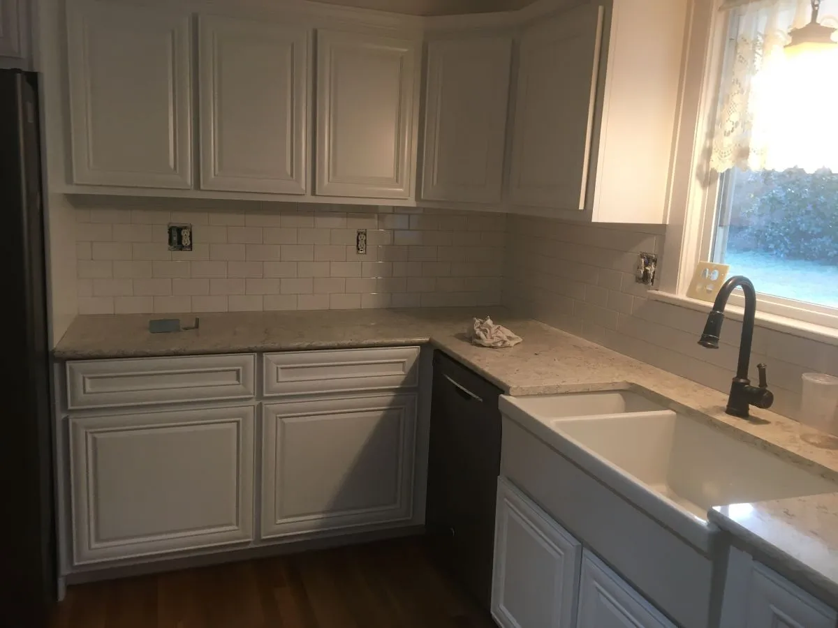 Kitchen renovation with corner sink and white raised-panel cabinets