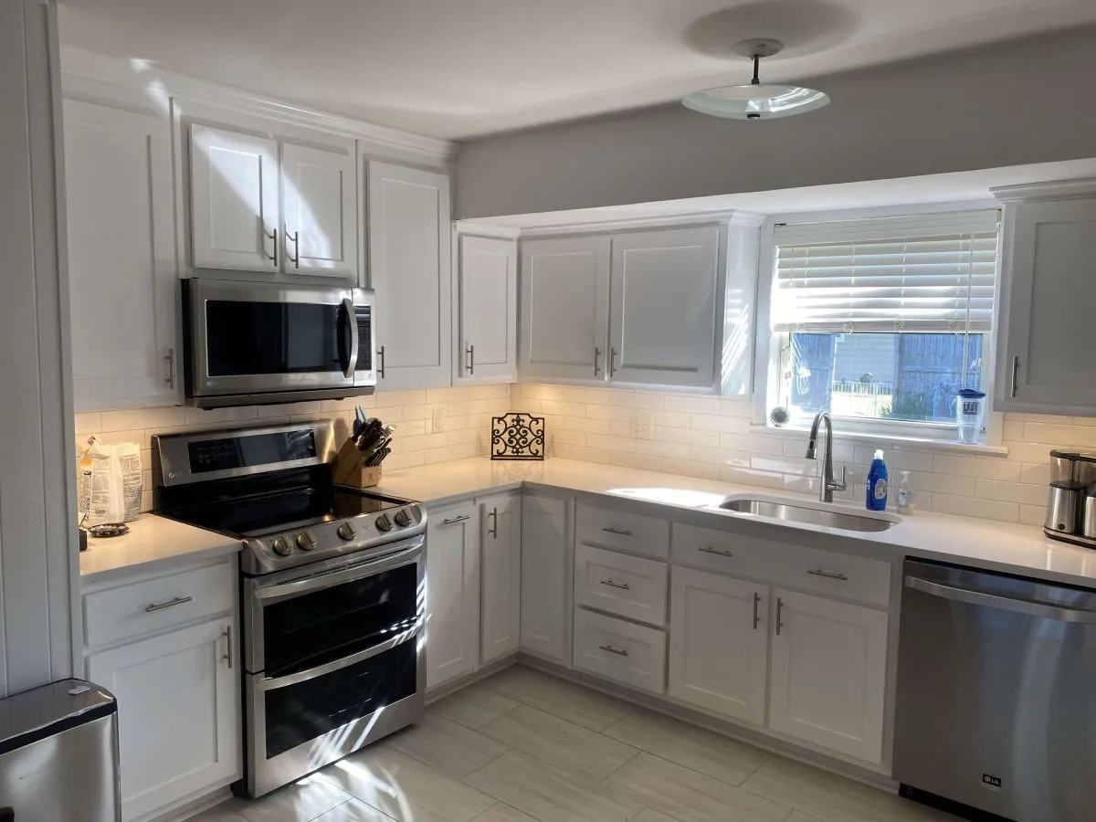 Corner kitchen with white cabinetry, tile backsplash, and stainless steel appliances