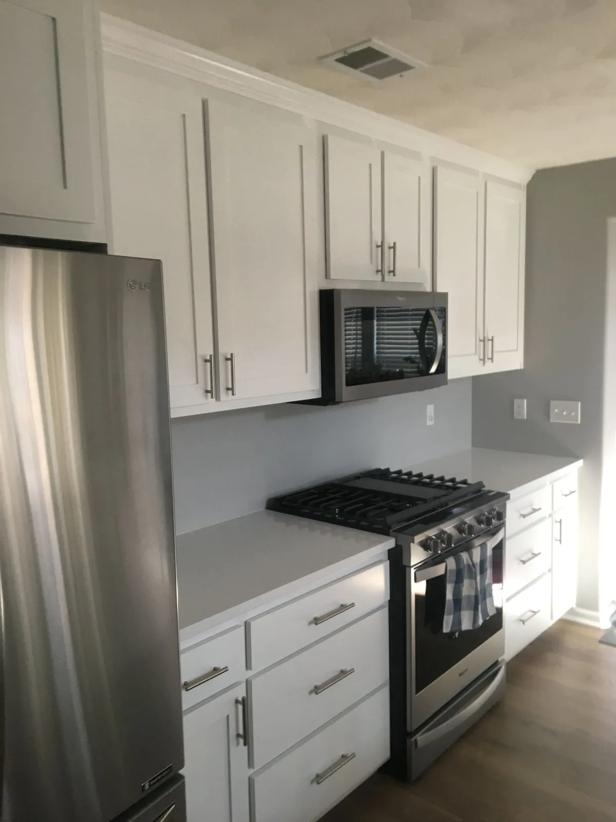 Compact kitchen remodel with gas range, built-in microwave, and simple white cabinetry