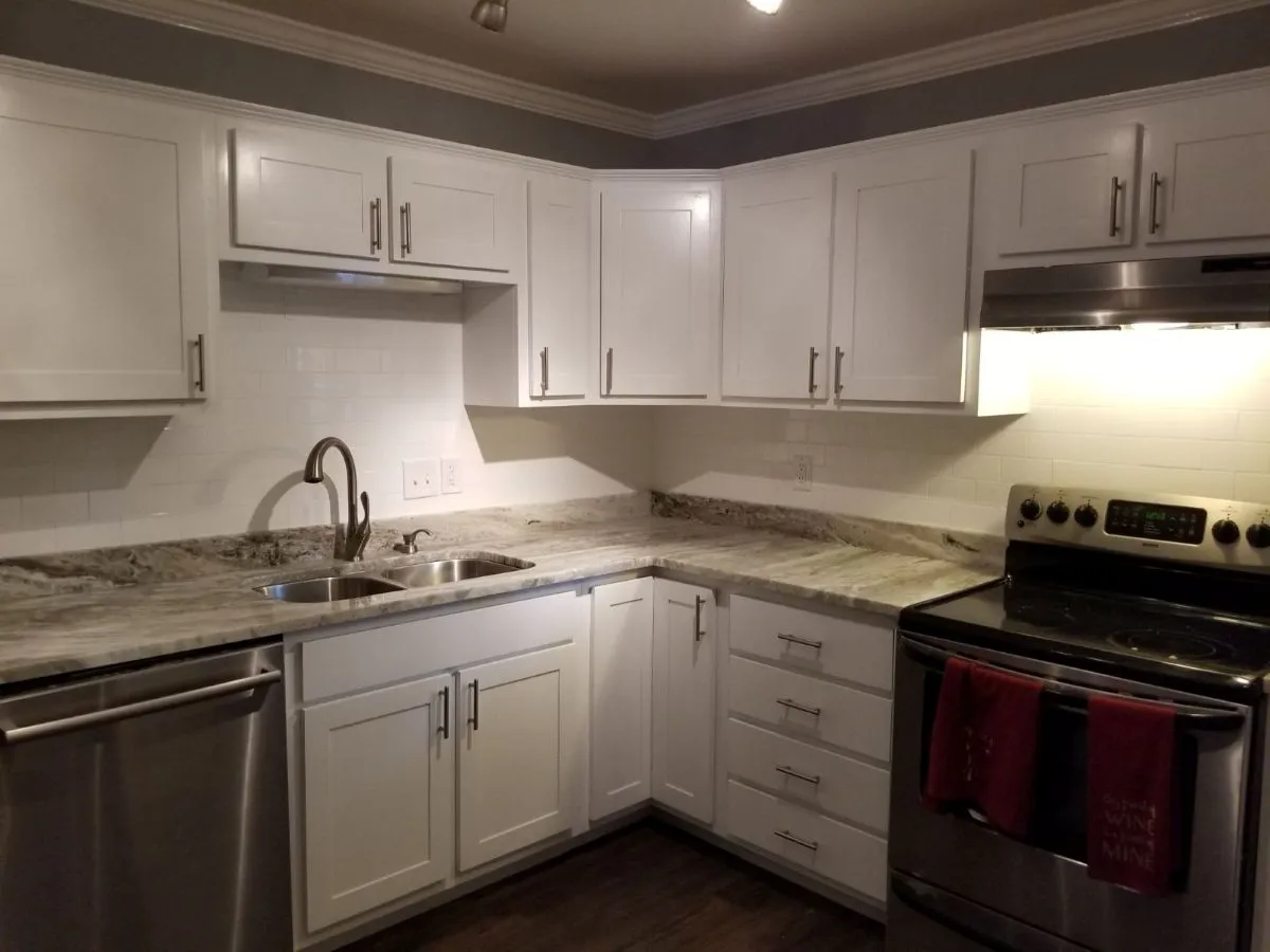 Modern kitchen renovation with granite-look counters, dual sinks, and subway tile backsplash