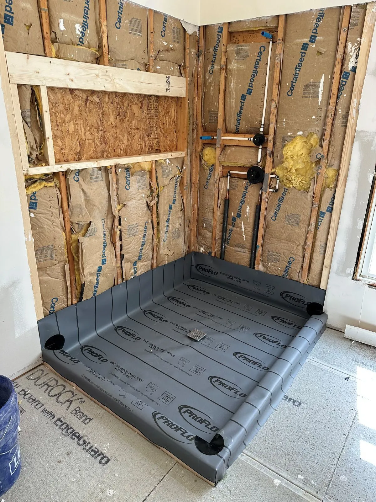 Exposed framing and subfloor in bathroom during water damage inspection.