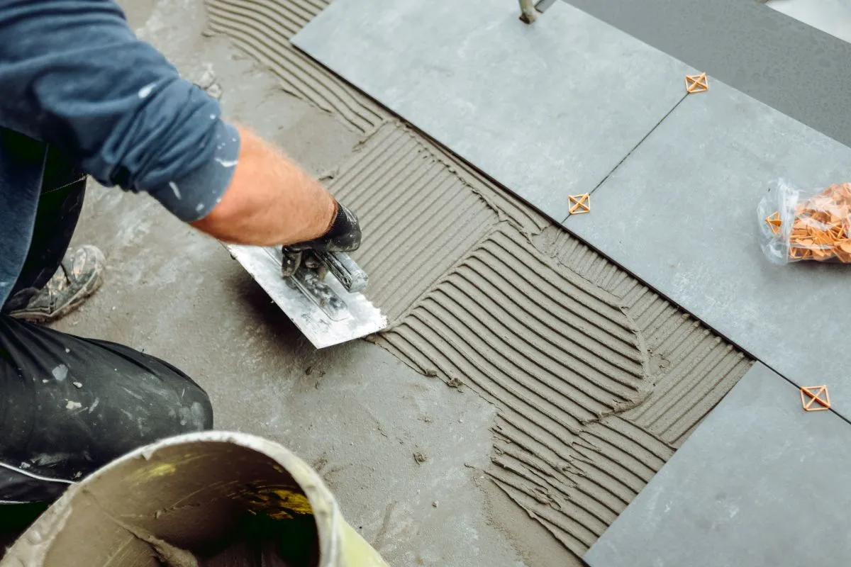 Contractor leveling subfloor with mortar before new tile installation