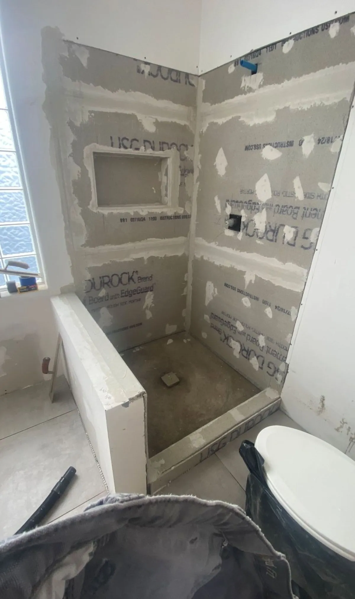 Water-damaged bathroom stripped for evaluation with exposed cement board and plumbing access in Suffolk VA