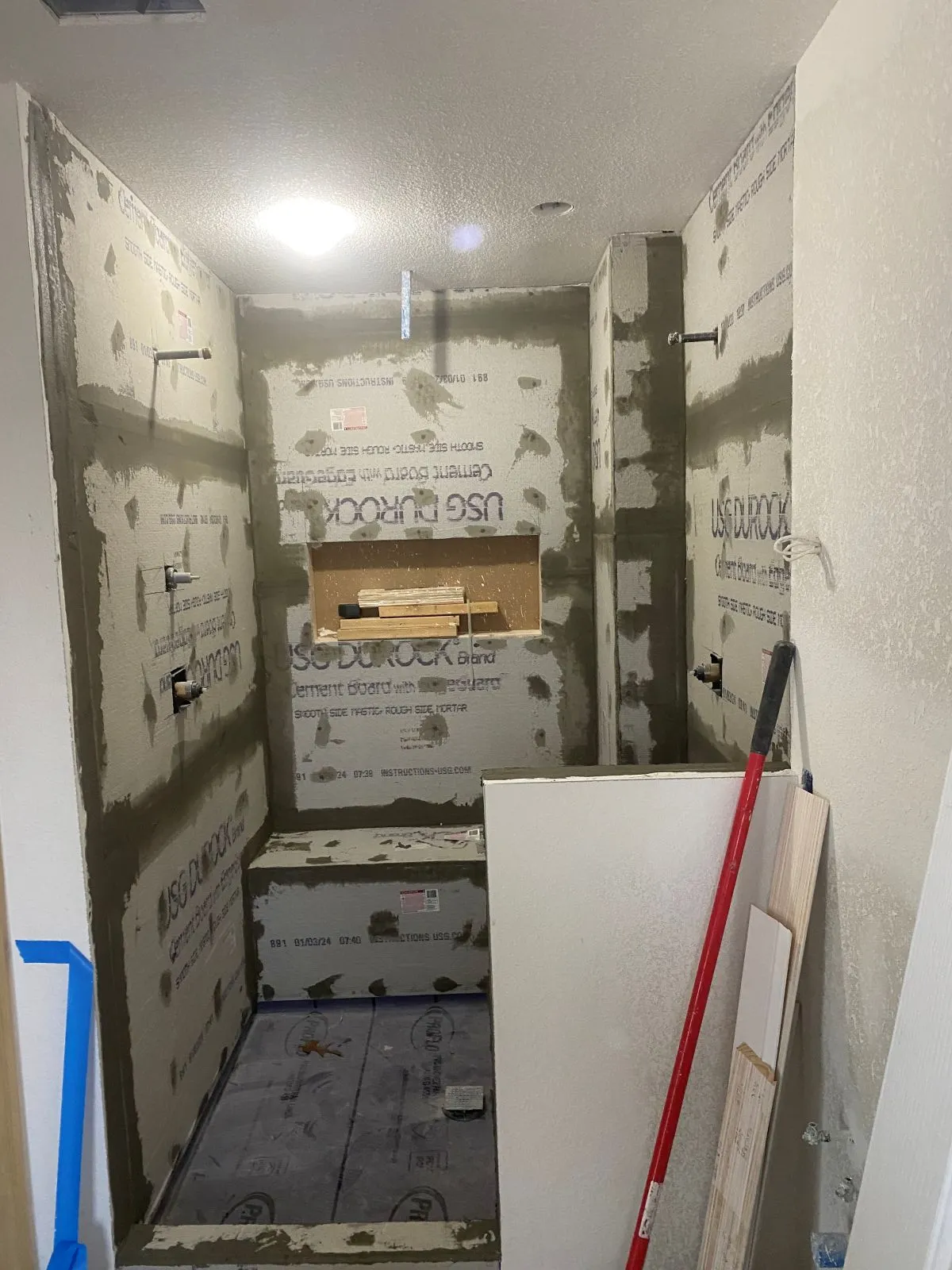 Shower area with cement board exposed and removed fixtures before water damage repairs in Virginia Beach