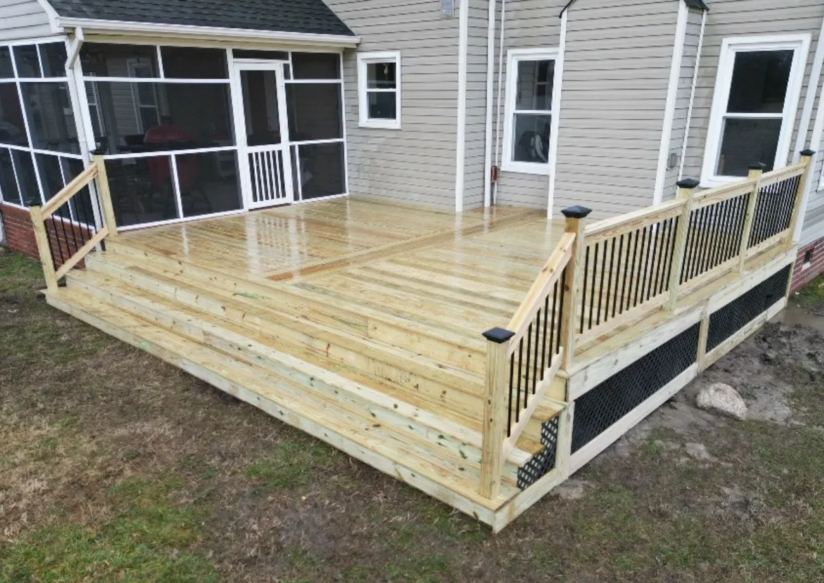 New pressure-treated wood deck with black railings and wide steps in Chesapeake backyard